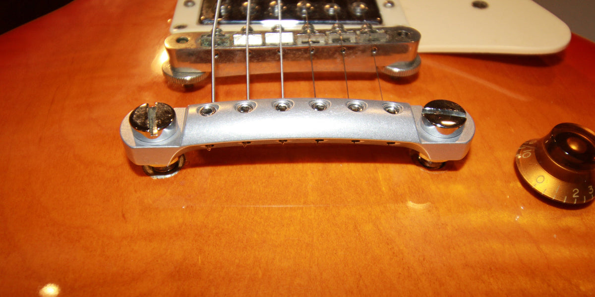 prototype Lightweight CNC raw aluminum stopbar with branded hex tool and reversable pick holding foam insert installed on Les Paul
