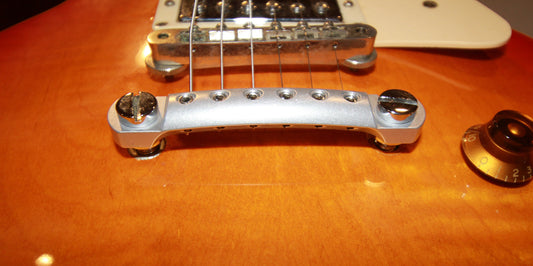 prototype Lightweight CNC raw aluminum stopbar with branded hex tool and reversable pick holding foam insert installed on Les Paul